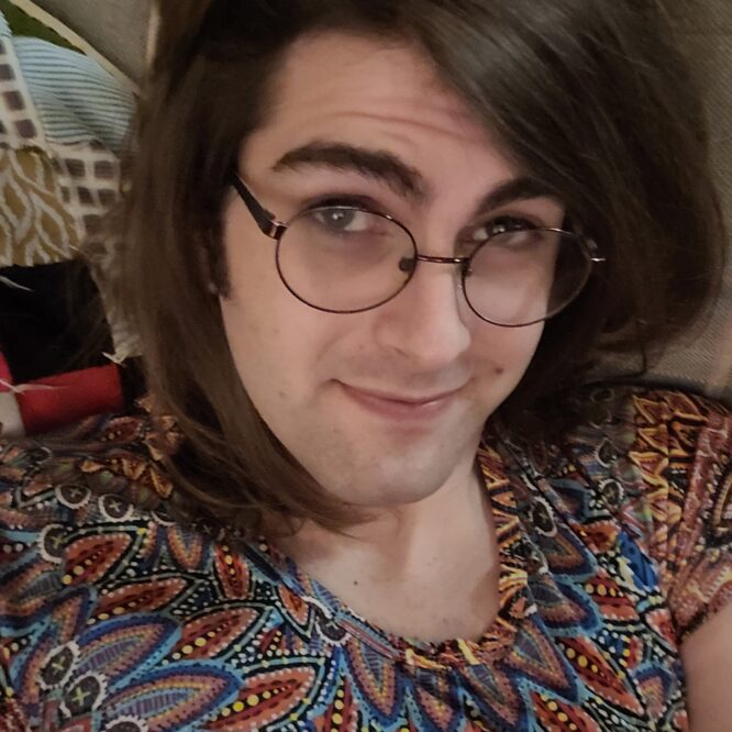 Person with glasses smiling, wearing patterned shirt