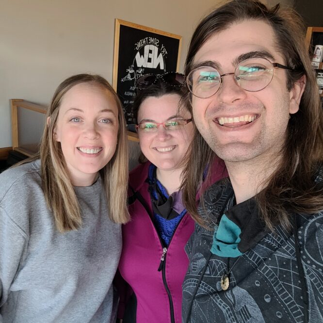 Three smiling friends posing for selfie indoors