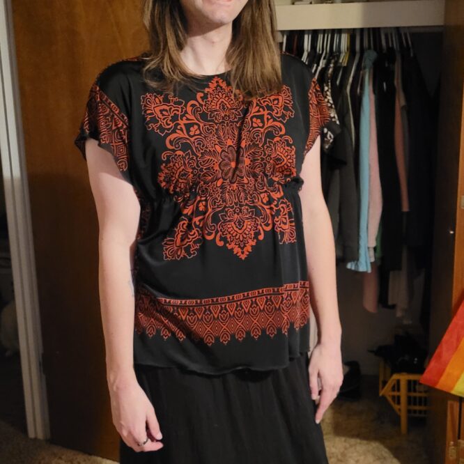Smiling person wearing glasses and black patterned dress