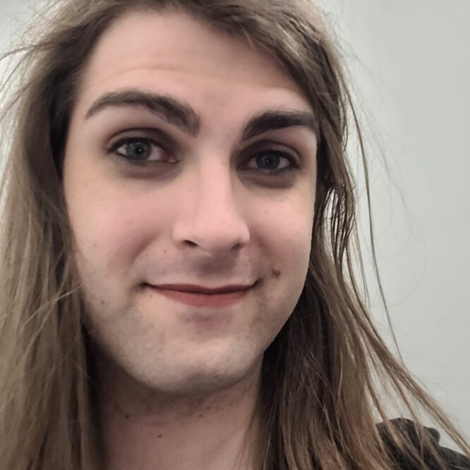 Smiling person with long hair wearing makeup