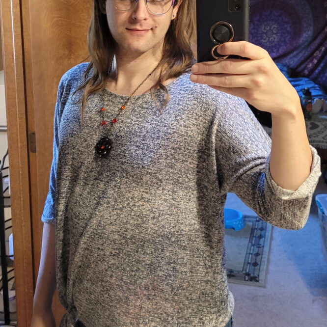 Person taking mirror selfie wearing gray sweater