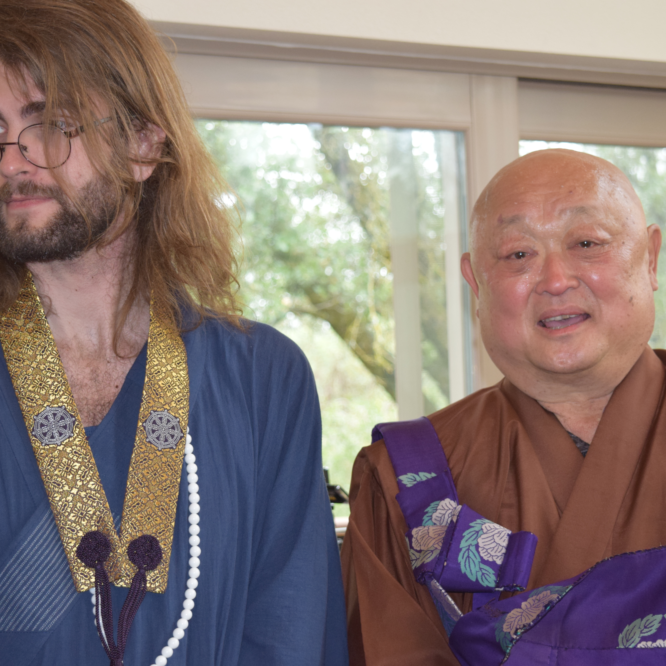 Two men in traditional robes, smiling indoors