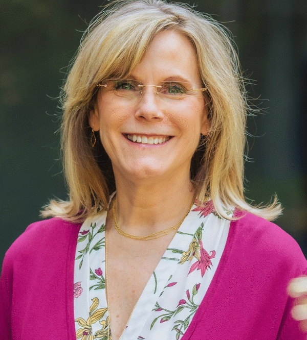 Smiling woman with glasses wearing magenta cardigan