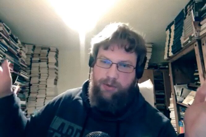 Bearded man with headphones surrounded by books